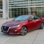 A red 2019 Nissan Altima in front of a glass building