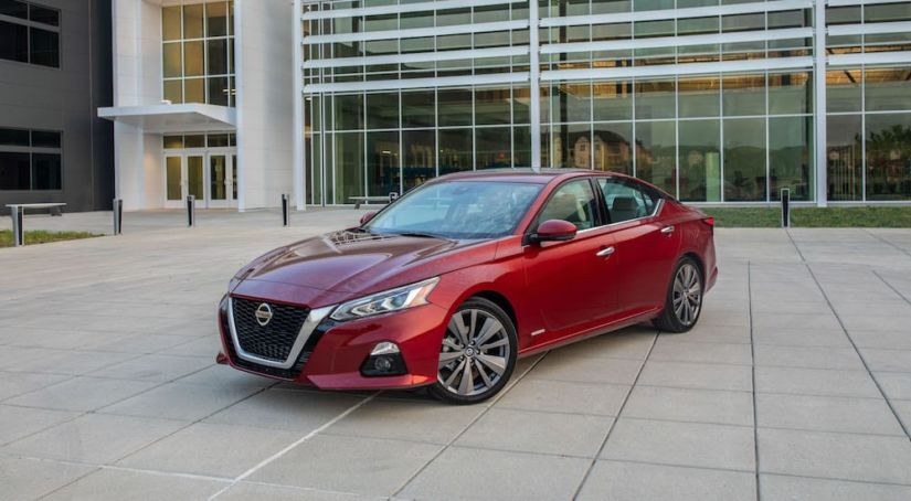 A red 2019 Nissan Altima in front of a glass building