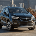 A black 2019 Buick Encore is parked with a city block in the distance.