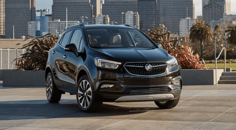 A black 2019 Buick Encore is parked with a city block in the distance.