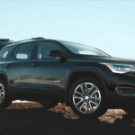 A man with a backpack is opening the trunk of his 2019 GMC Acadia