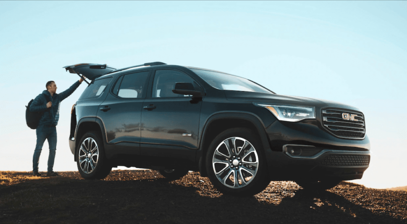 A man with a backpack is opening the trunk of his 2019 GMC Acadia