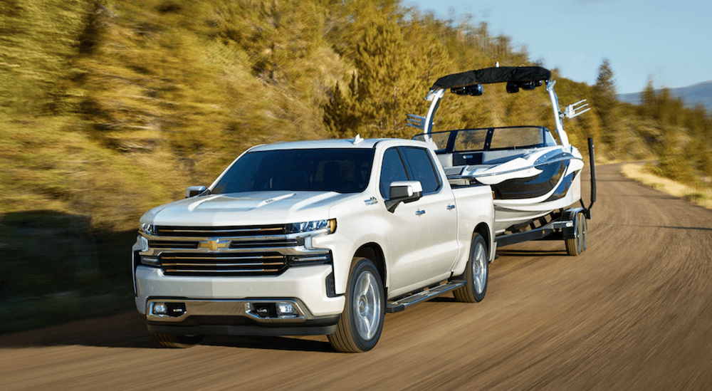 A white 2019 Chevy Silverado is towing a white boat showing its superior towing capabilities when comparing the 2019 Chevy Silverado vs 2019 Honda Ridgeline.