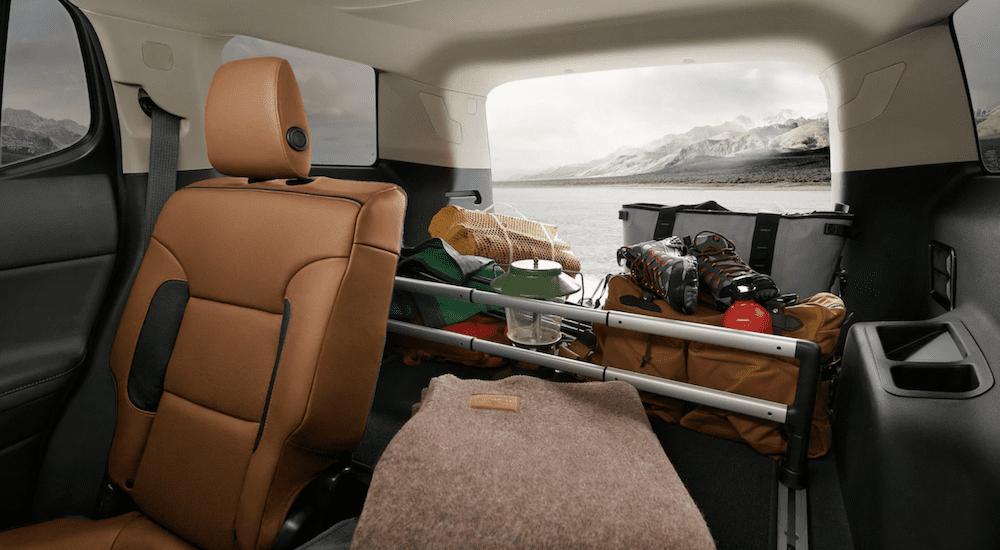 The GMC interior cargo space in tan, cream, and black is shown filled with hiking gear demonstrating why it is the better option for the 2019 GMC Acadia vs 2019 Jeep Grand Cherokee comparison.