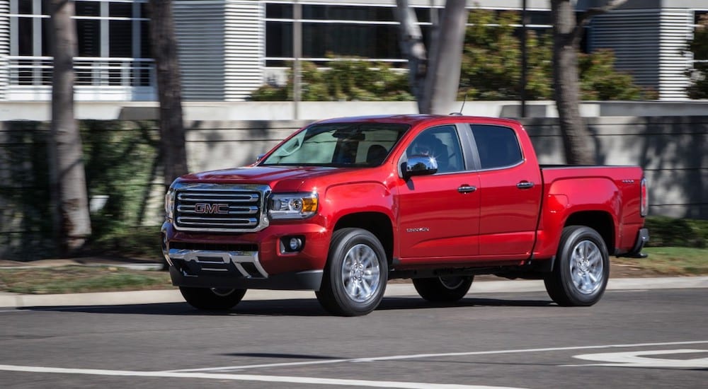A red 2019 GMC Canyon driving away from a GMC Dealer Near Me