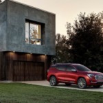 A red 2019 GMC Terrain Denali in front of a modern home at night