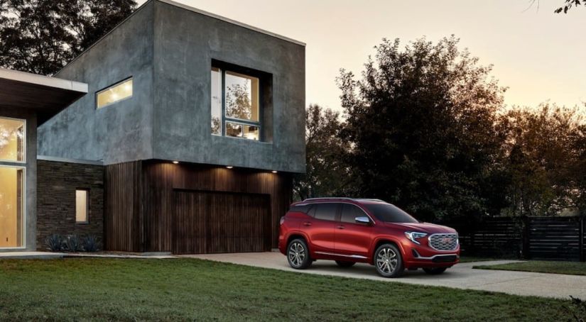 A red 2019 GMC Terrain Denali in front of a modern home at night