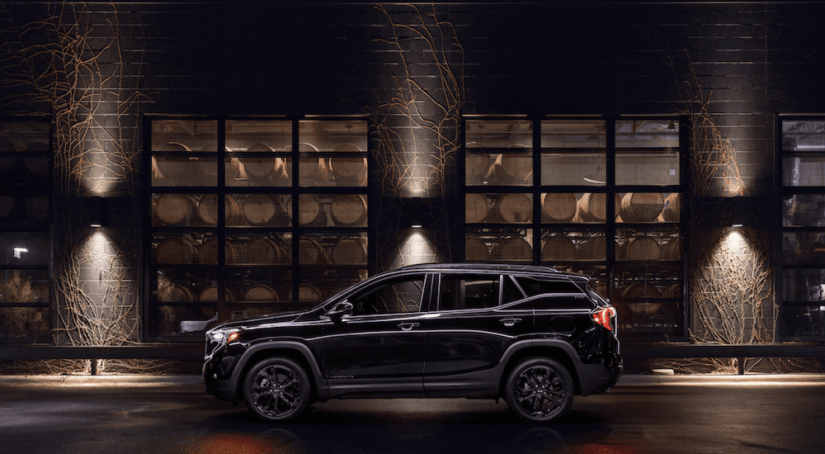 A 2019 black GMC Terrain is parked in front of a building at night.