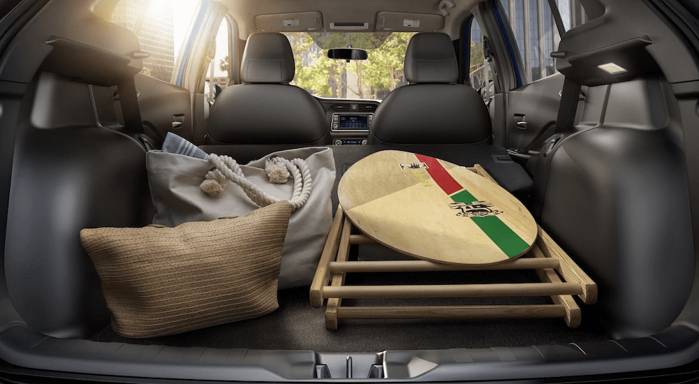 Beach bags, a skim board, and more are shown in the folded down cargo space of the 2019 Nissan Kicks.