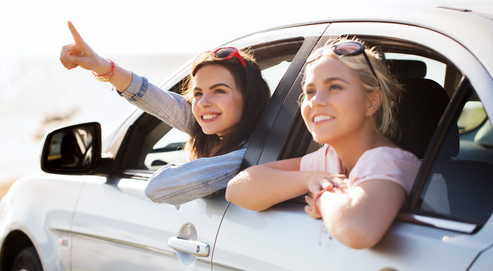 Two happy teen girls in a white sedan