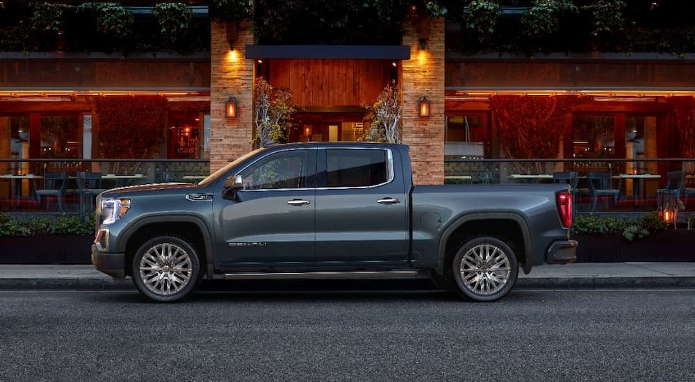 A grey 2019 GMC Sierra Denali is parked outside a restaurant with outdoor seating. 