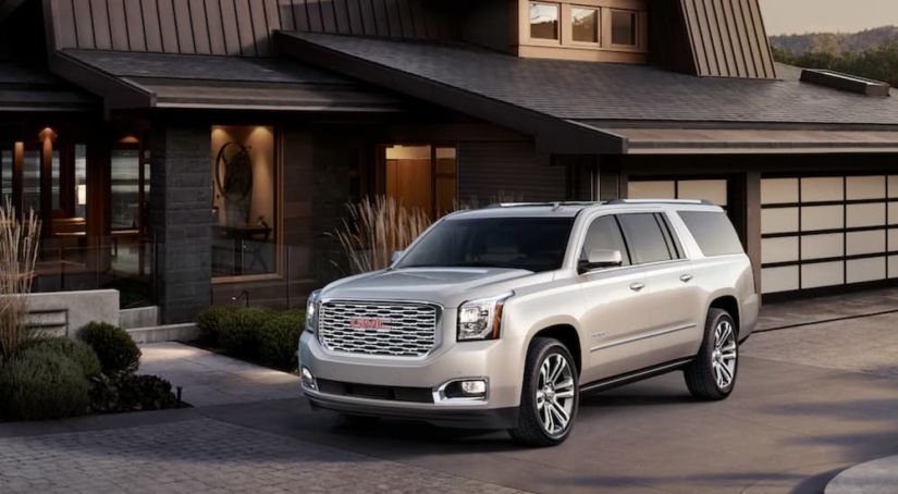A light colored 2019 GMC Yukon XL Denali is parked in front of a modern house.