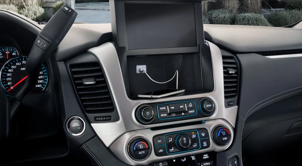 The screen on the 2019 GMC Yukon XL's dashboard is up, showing a phone charging in a discrete cubby. Compare the interior features when looking at the 2019 GMC Yukon XL vs 2019 Toyota Sequoia.