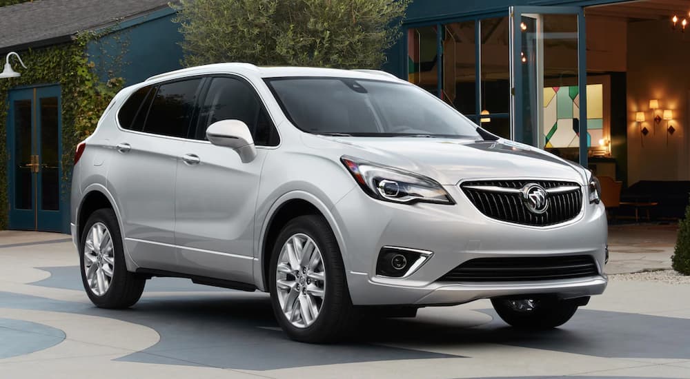 A silver 2019 Buick Envision is parked in front of a shop.