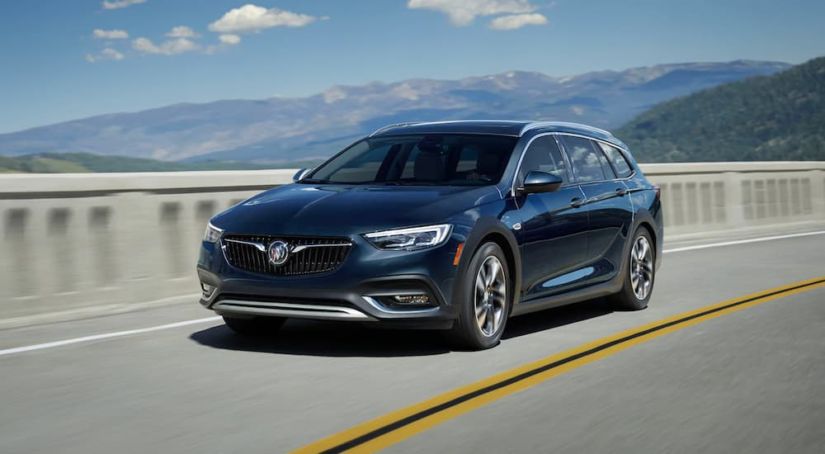 a dark colored 2019 Buick Regal Tourx is driving up high with mountain views. It is part the Buick SUVs and crossovers.