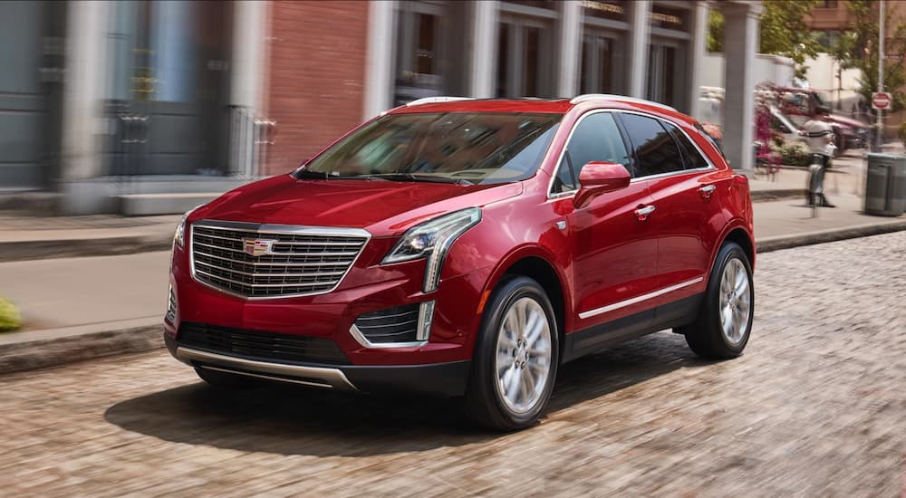 A red 2019 Cadillac XT5 is in front of a brick building. Searching "Cadillac dealer near me" will help locate current offers.