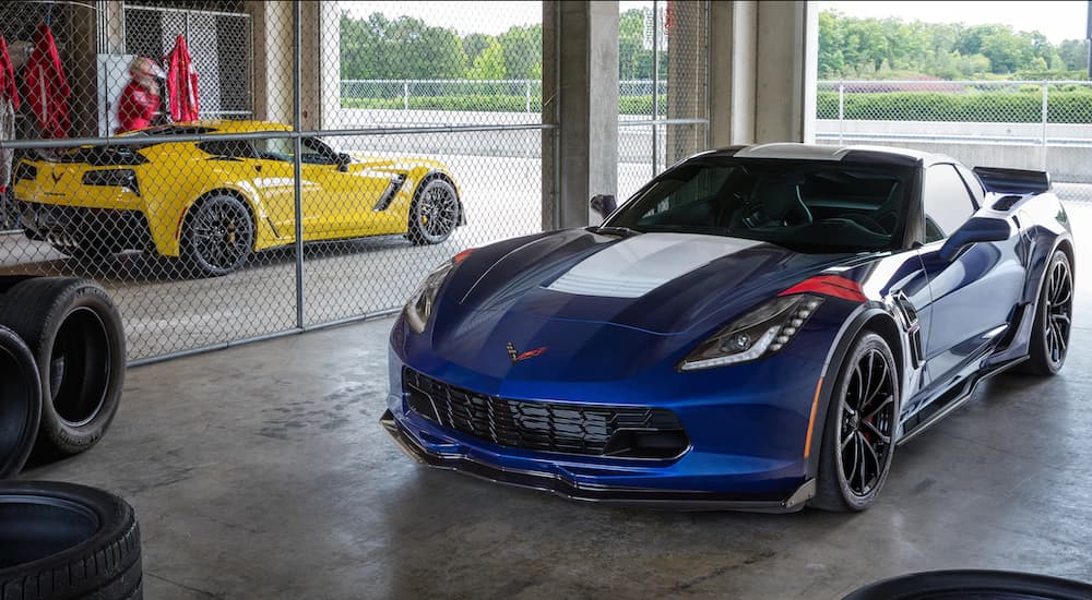 A yellow and a blue 2019 Corvette Grand Sport are parked at a race track under cover.