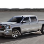 A silver 2017 GMC Sierra is parked with mountains in the far distance.