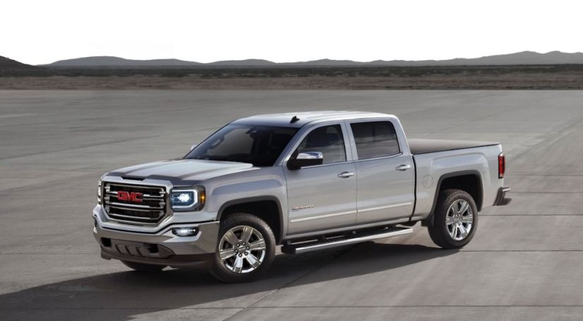 A silver 2017 GMC Sierra is parked with mountains in the far distance.