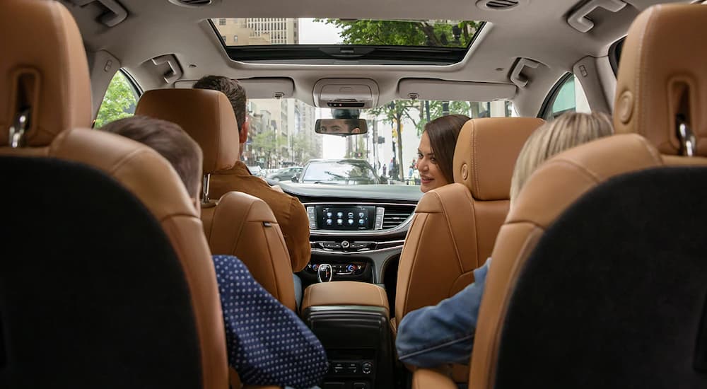 The tan interior of a 2019 Buick Enclave is shown front he back with a family inside. Check out interior when comparing the 2019 Buick Enclave vs 2019 Ford Explorer.