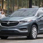A grey 2019 Buick Enclave is shown in the rain in a city.
