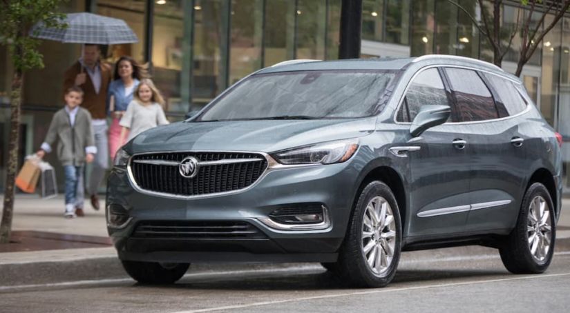 A grey 2019 Buick Enclave is shown in the rain in a city.