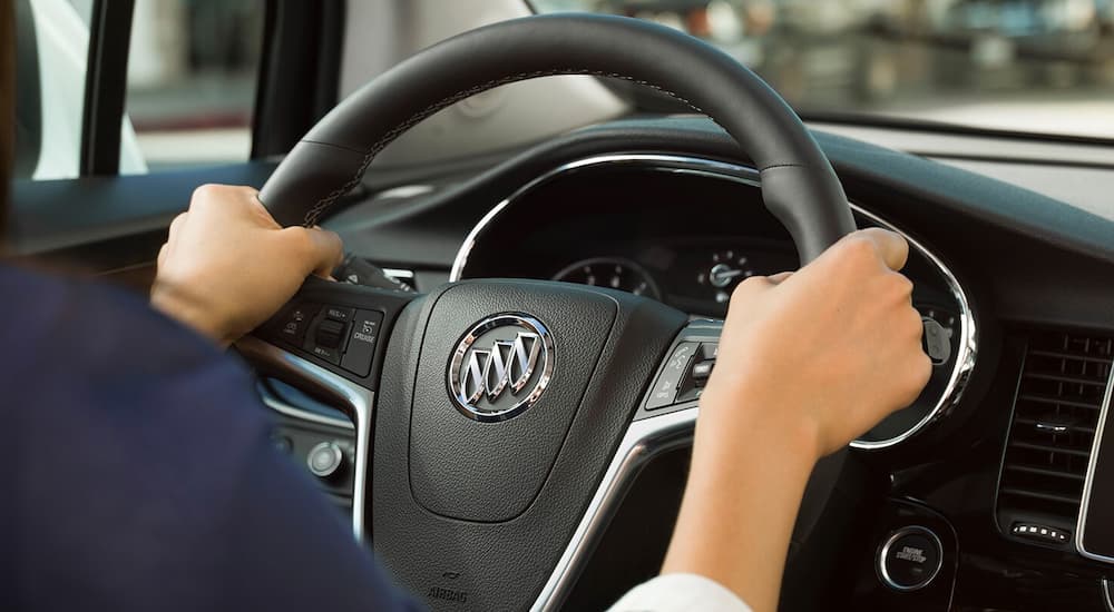 A closeup of a woman's hands on her 2019 Buick Encore steering wheel, which has more features when comparing the 2019 Buick Encore vs 2019 Mini Countryman.