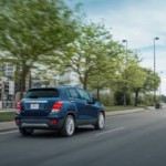 A blue 2019 Chevy Trax is driving into a city.