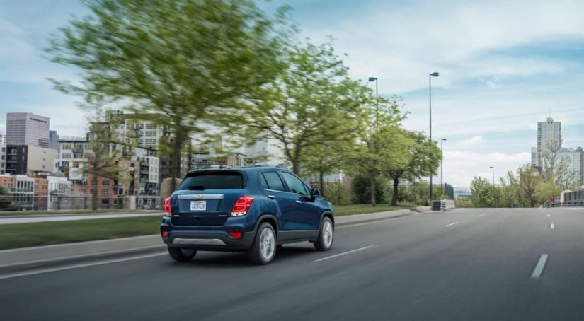 A blue 2019 Chevy Trax is driving into a city.