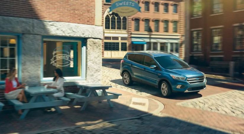 A blue 2019 Ford Escape is parked outside a sweets shop downtown.