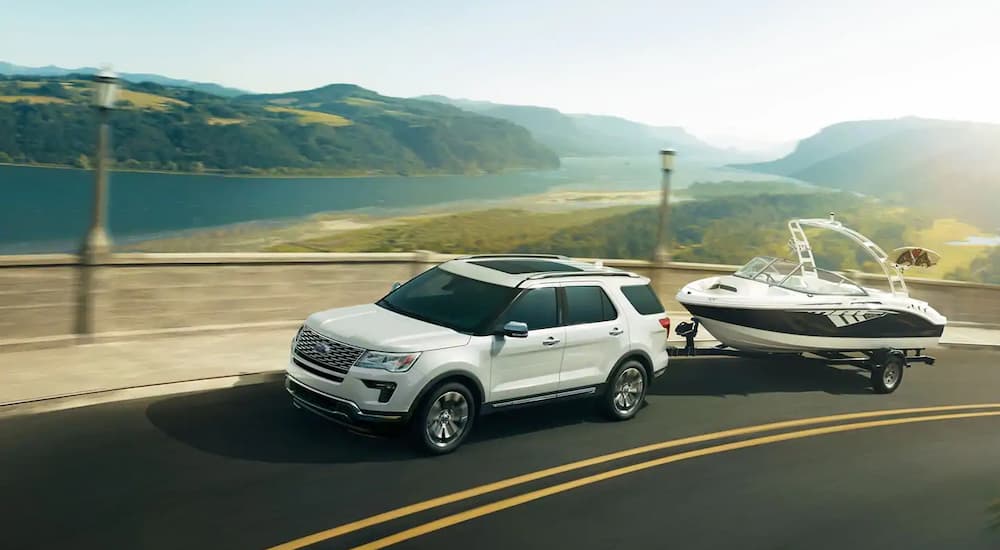 A white 2019 Ford explorer is towing a boat. Check out towing capacity when comparing the 2019 Ford Explorer vs 2019 GMC Acadia.