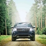 A dark 2019 Ford Explorer is on a dirt road in the woods.