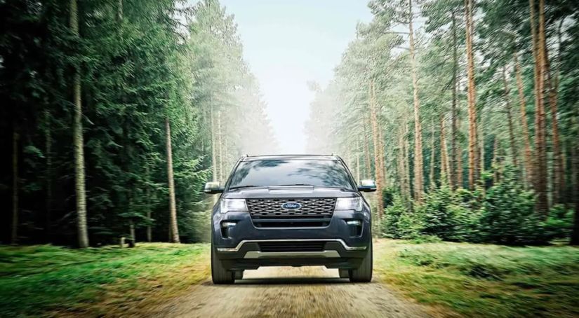 A dark 2019 Ford Explorer is on a dirt road in the woods.