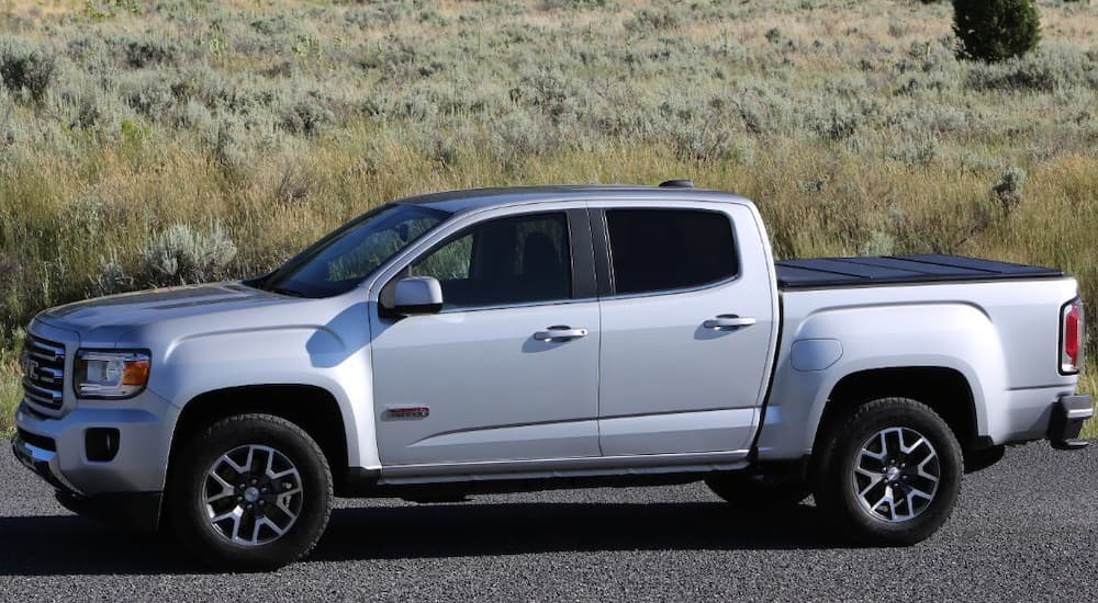 A silver 2019 GMC Canyon is in fron tof a field. Comparing exterior styling when looking at the 2019 GMC Canyon vs 2019 Chevy Colorado.
