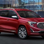 A red 2019 GMC Denali is parked outside a glass building.