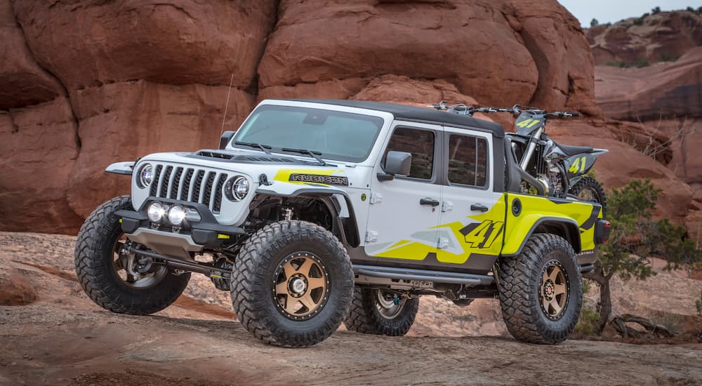 The white and yellow concept 2019 Jeep Flatbill with dirt bikes in the back is shown at the 2019 Moab Utah Easter Jeep Safari in current auto news.