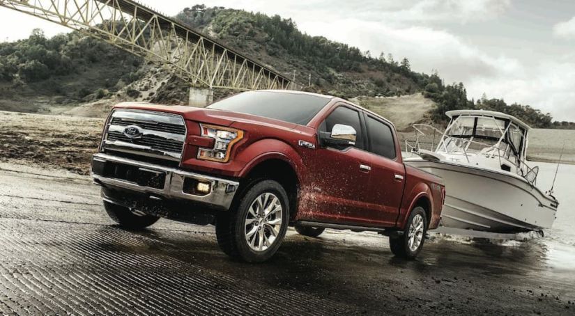A dark red 2017 Ford F-150 Lariat is towing a boat out of the water. Check out this model and other used Ford trucks for sale.