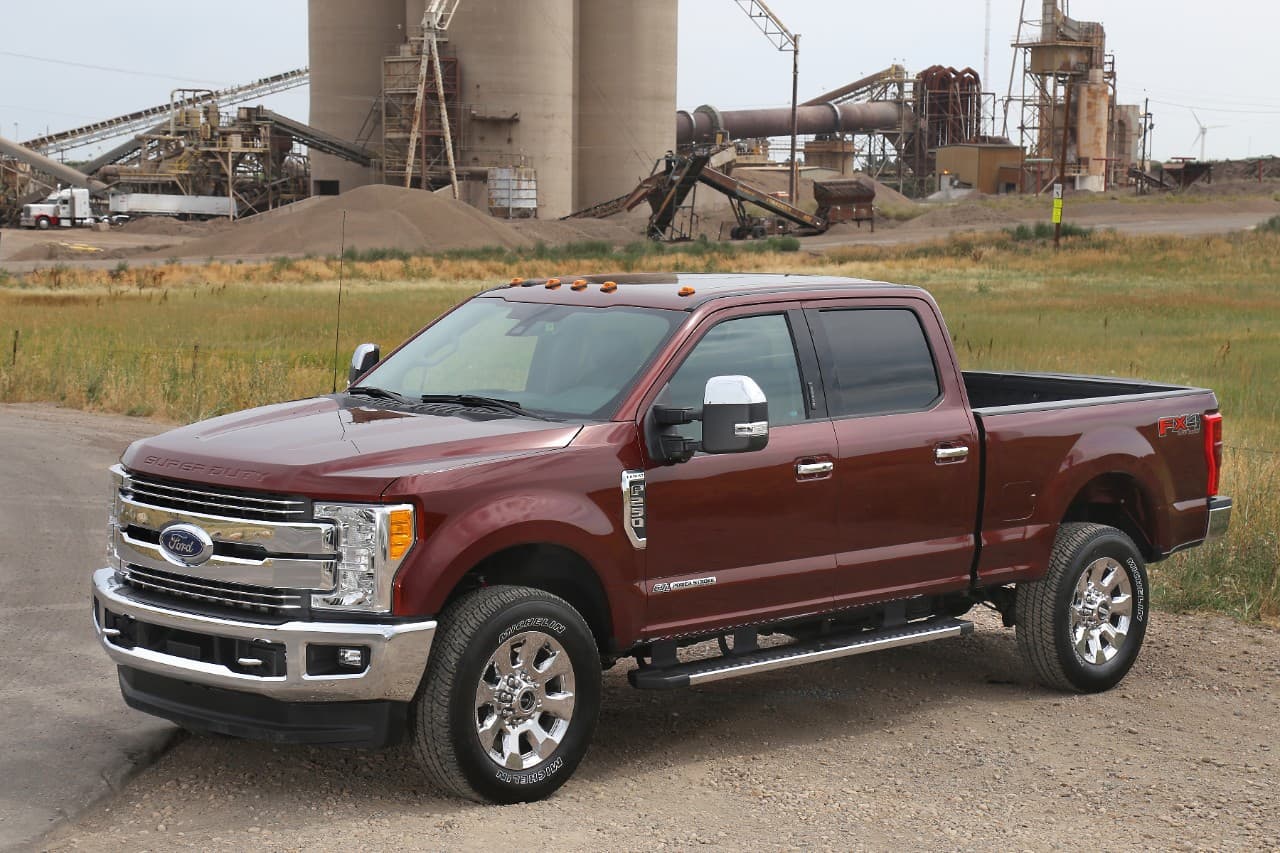 A burgundy 2017 Ford F-250 is parked in front of a materials plant with silos.