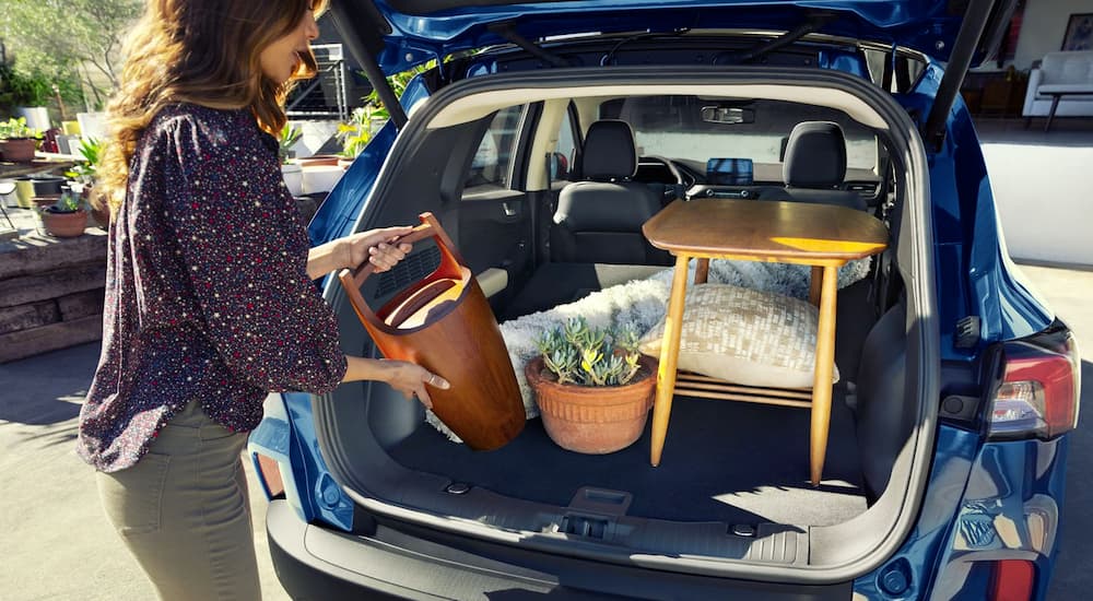 A woman is loading furniture into the cargo area of her 2020 Ford Escape.