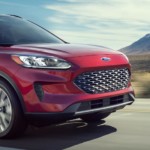 A red 2020 Ford Escape is driving with mountain views.