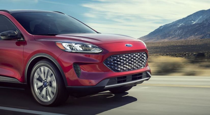 A red 2020 Ford Escape is driving with mountain views.
