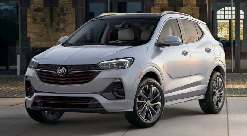 A white 2020 Buick Encore is parked on a city road in front of an old brick building