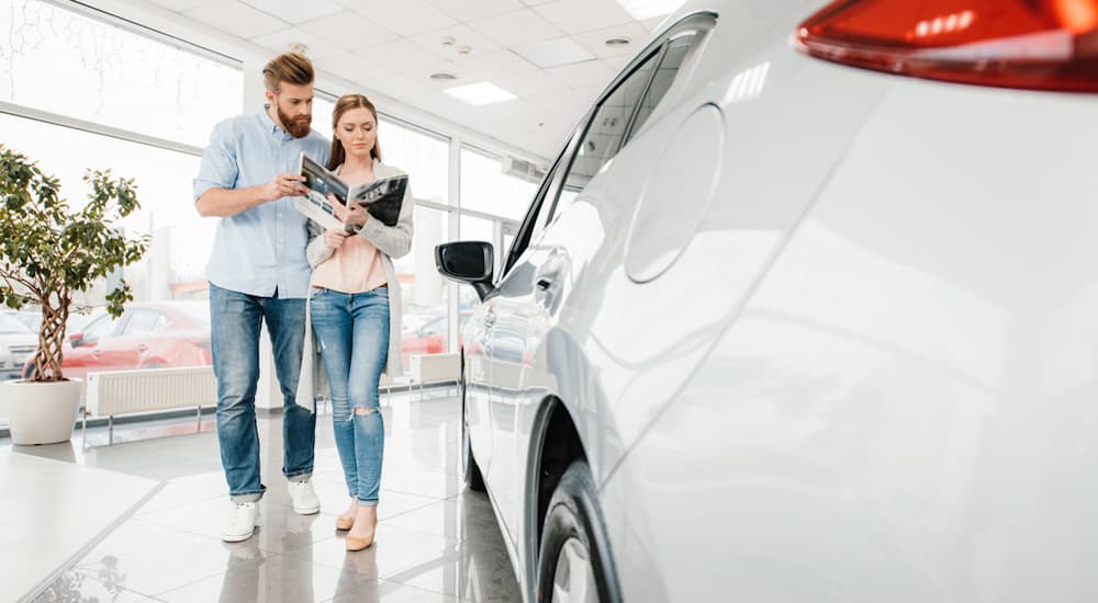 A couple at one of the dealerships in Nashville is looking at a book with information on the white car in front of them.