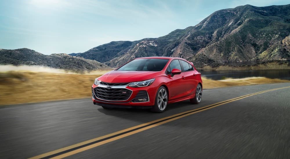 A red 2019 Chevy Cruze hatchback is driving in front of mountains.