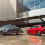 A grey 2019 Chevy Cruze sedan is parked next to a red hatchback.