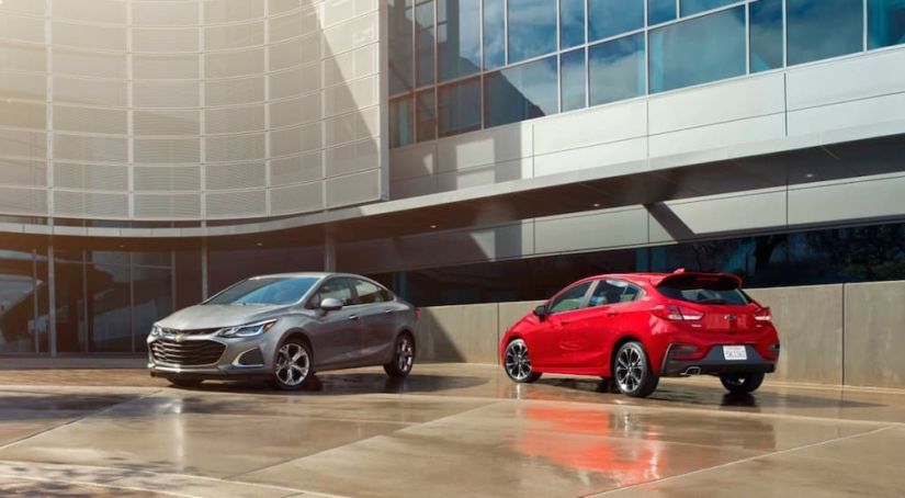 A grey 2019 Chevy Cruze sedan is parked next to a red hatchback.