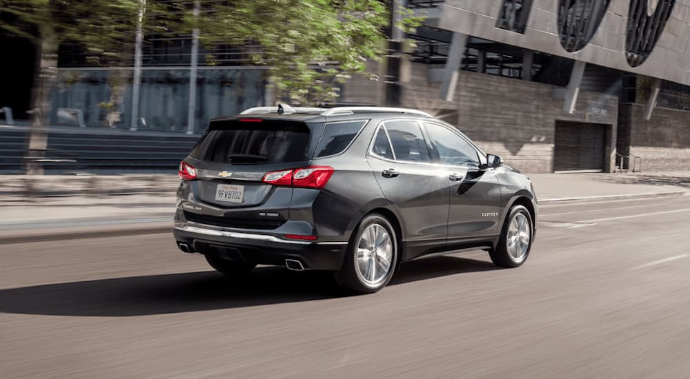 A grey 2019 Chevy Equinox is driving down a city block.