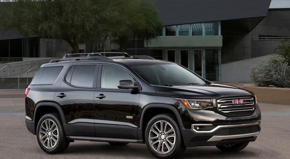 A black 2019 GMC Acadia is parked in front of a house. 