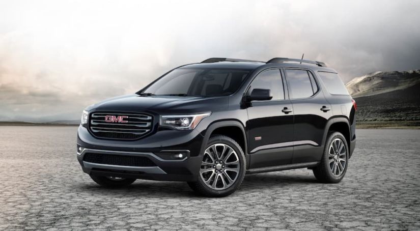 A black GMC Acadia, which wins when comparing the 2019 GMC Acadia vs 2019 Ford Explorer, is in a salt flat valley.