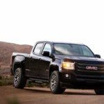 A black 2019 GMC Canyon is parked on dirt.